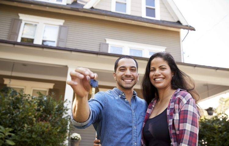 Portrait Of Couple Holding Keys To New Home On Moving In Day