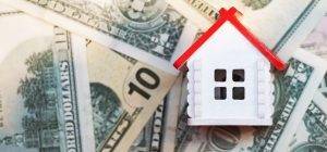 Invest in real estate, mortgage concept. White house with a red roof on the background of dollar bills