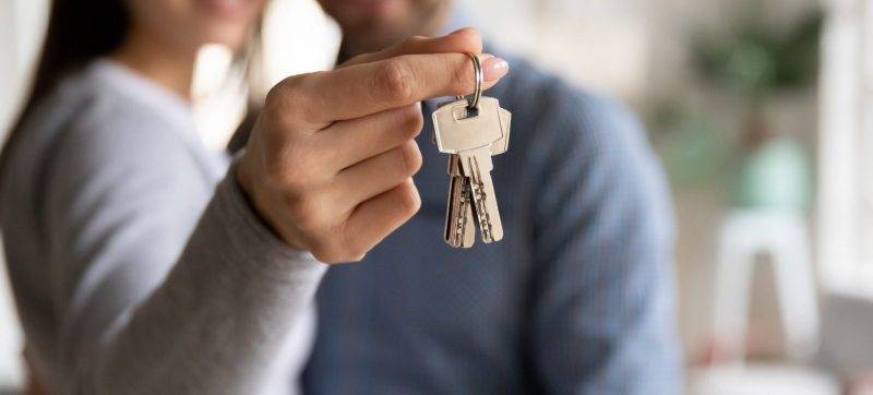 Close up happy young woman hugging man, holding keys